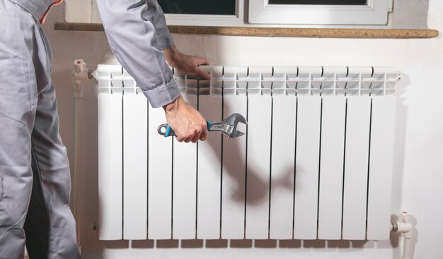 Man repairing radiator with adjustable wrench.