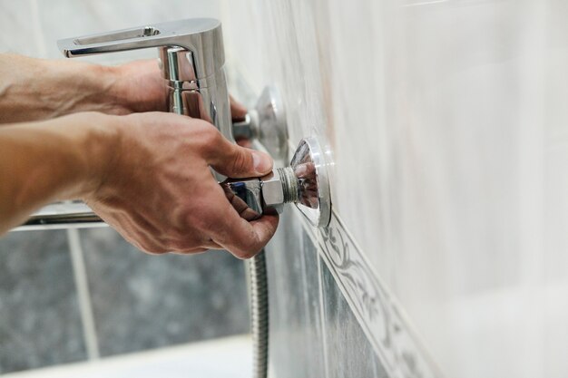 Photo a man repairs a faucet in the bathroom