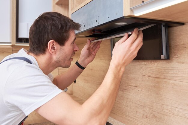 Photo man repairs hood in the kitchen replacement filter in cooker hood