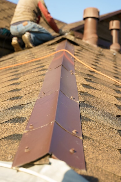 A man repairs a roof covered with shingles