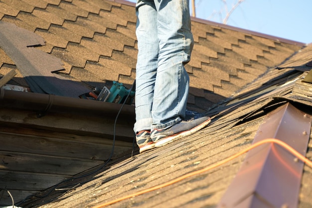 Photo a man repairs a roof covered with shingles