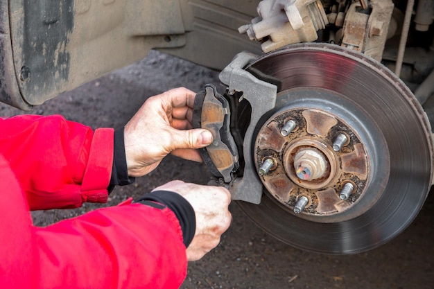 Photo a man replaces the brake pads on a car security service