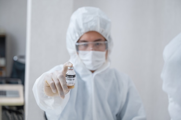 Man researcher in medical ppe showing effective vaccine bottle against Covid-19 in the laboratory