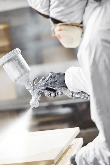 man in respirator mask painting wooden planks at workshop application of flame retardant ensuring