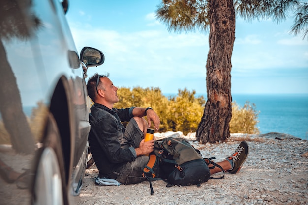 Man resting after hiking by the car