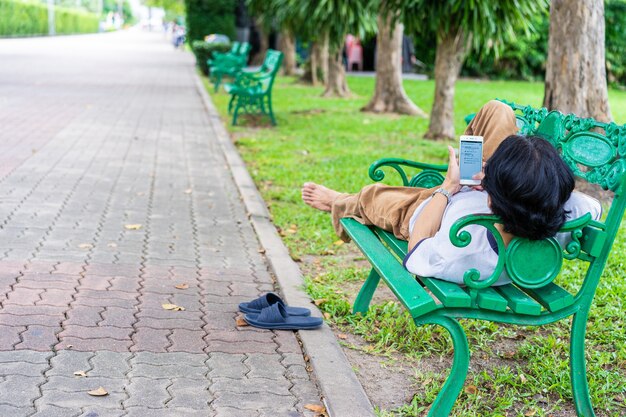 公園のベンチに座って携帯電話でNEWSを読んでいる男