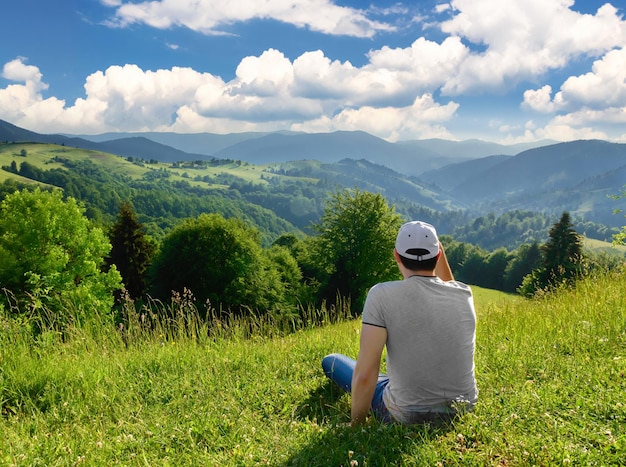 Man resting on top of a mountain on the background of mountain scenery. Summer season