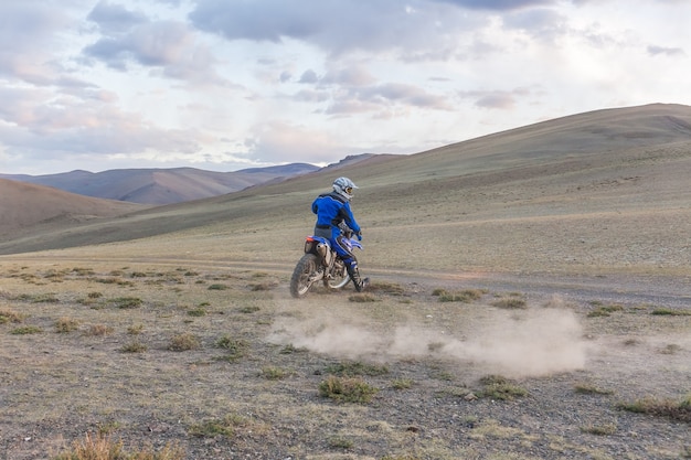 写真 モンゴルの丘の上のモンゴルの草原でモトクロスバイクに乗る男