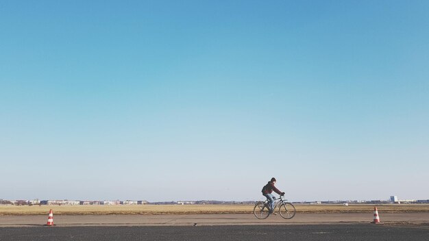 Foto uomo in bicicletta contro un cielo limpido