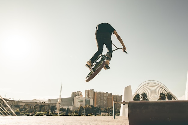 Photo man riding bicycle on metallic pipe against sky