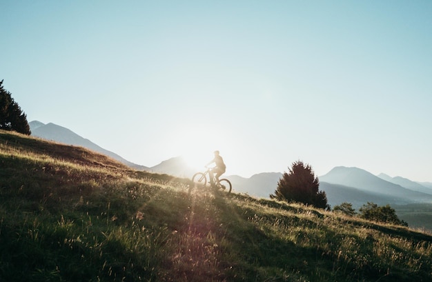 Photo man riding bicycle on mountain against sky