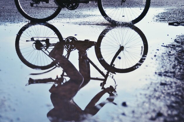 Photo man riding bicycle reflecting on puddle at street