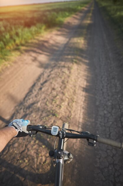 Man riding a bike holding bike handlebar with one hand in sport glove summertime outdoor leisure sport activity firstperson view bicycle riding