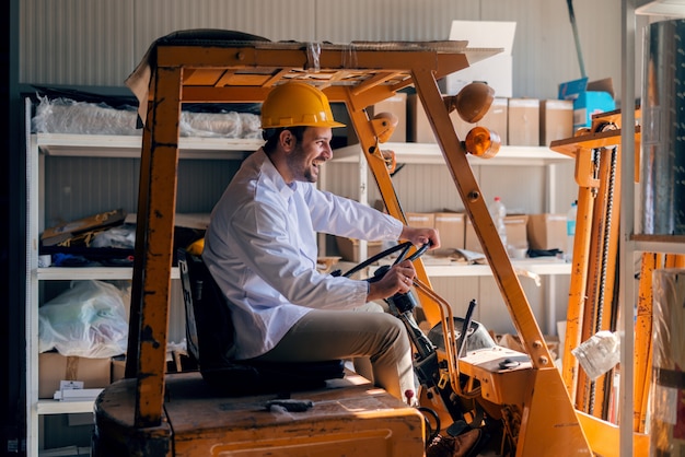 Man riding forklift. On head helmet. Storage interior.