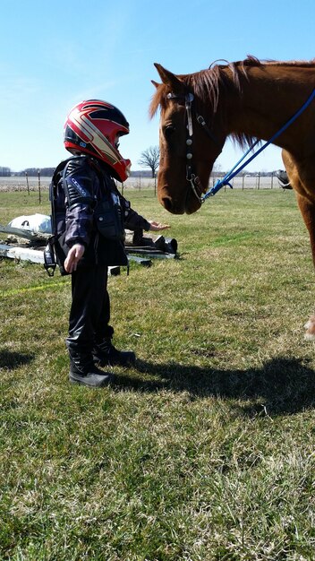 Foto uomo a cavallo in piedi sul campo