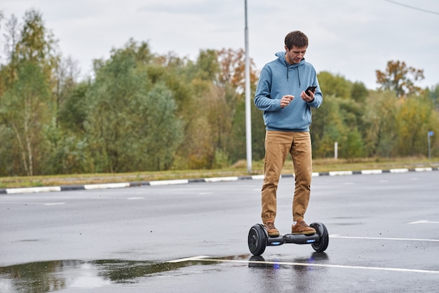 Man riding on the hoverboard and using smartphone outdoor