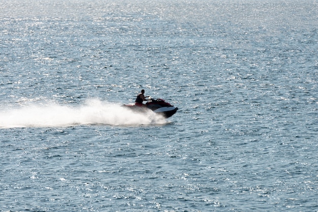 Man riding a jet ski shooting in backlit by sunset