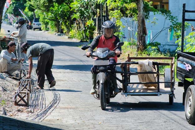 Photo man riding modified scooter to carry materials for builders in yogyakarta 20 july 2023