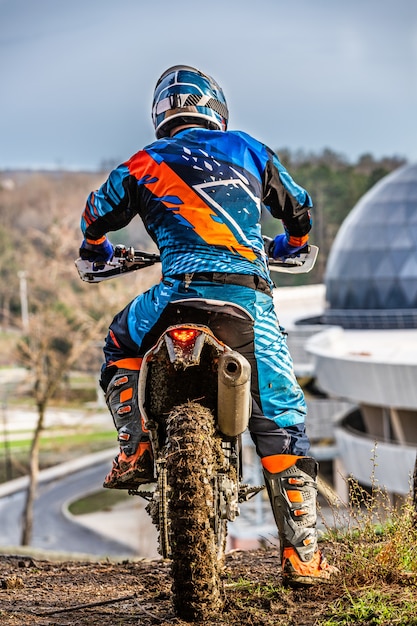 Foto uomo che guida un motocross in una tuta protettiva nel fango