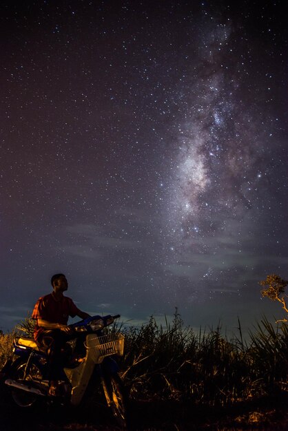 Foto uomo che guida uno scooter sul campo contro il campo stellare