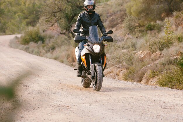 Человек едет на мотоцикле по дороге против неба