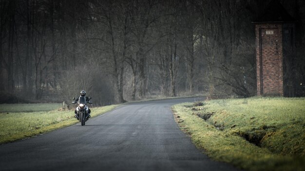 Photo man riding motorcycle on road amidst field