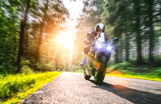 Foto uomo in moto su una strada nella foresta