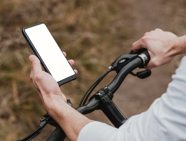 Uomo che guida una mountain bike e controlla il suo telefono