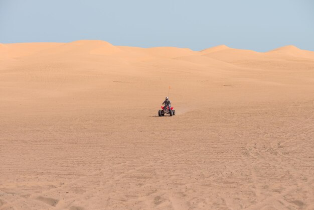 Photo man riding quadbike in desert against clear sky