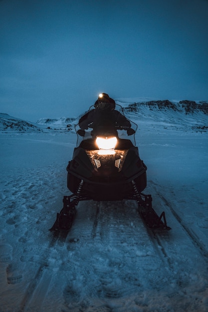 Photo man riding a snowmobile in the evening