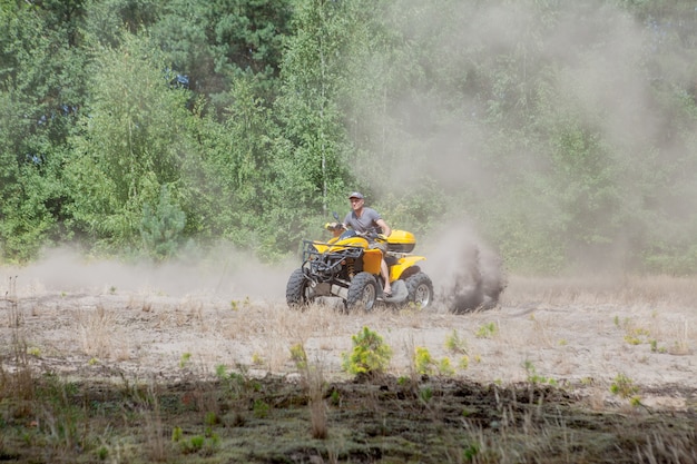 Uomo che guida un quad fuoristrada giallo atv su una foresta sabbiosa. moto estremo, avventura, attrazione turistica.