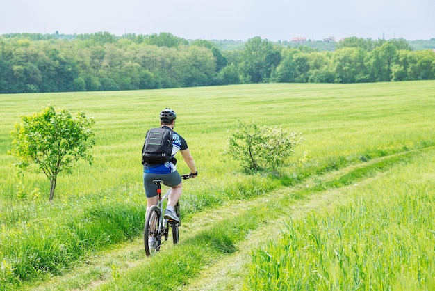 Man rijden fiets door parcours in groene gerst veld kopie ruimte