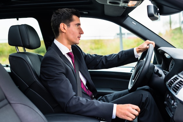 Man rijden in zijn auto in zakelijke kleding