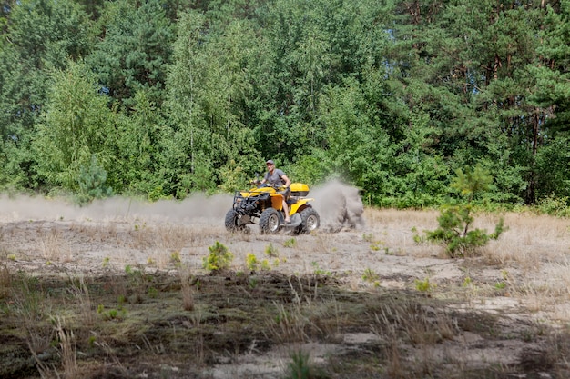 Man rijden op een gele quad atv alle terreinvoertuig op een zandig bos. extreme sportbeweging, avontuur, toeristische attractie.