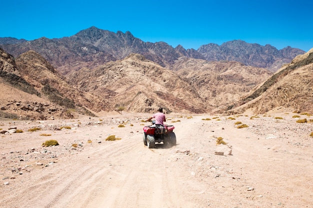 Man rijden op een quad in de woestijn.