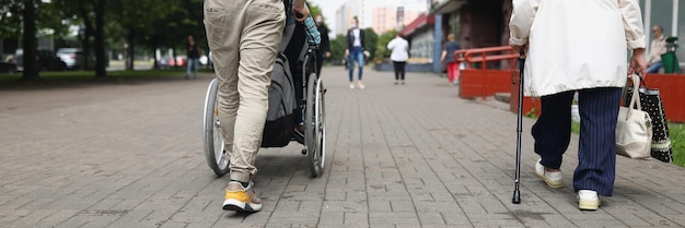Man rijdt gehandicapte vrouw in rolstoel over straat wandelend winkelend
