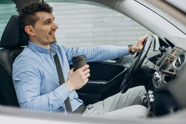 Man rijdt in zijn auto en drinkt koffie