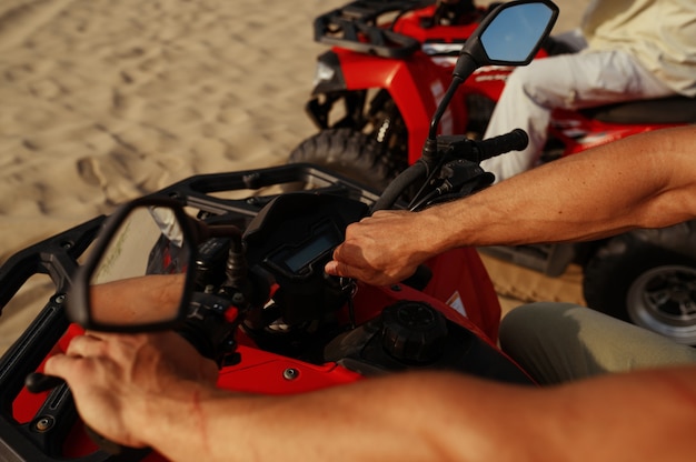 Man rijdt op atv in woestijn, close-up zicht op handen