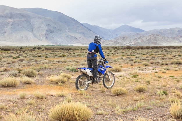 Man rijdt op een crossmotor in de steppen van Mongolië, op de heuvels van Mongolië