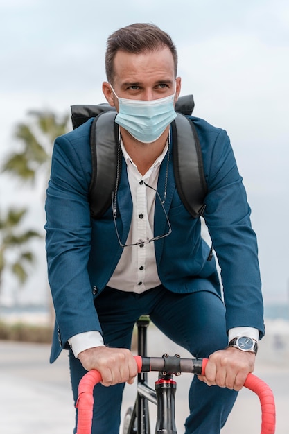 Foto man rijdt op een fiets terwijl hij een medisch masker draagt