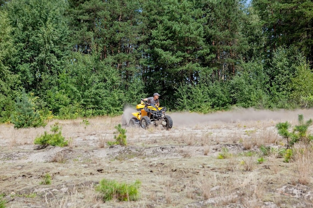 Foto man rijdt op een gele quad atv terreinwagen op een zanderig bos extreme sport bewegings-avontuur toeristische attractie
