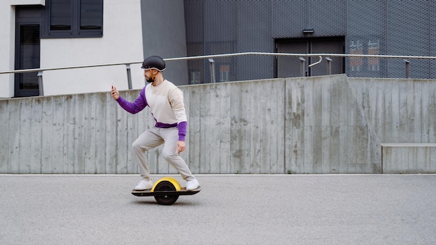 Man rijdt op elektrisch skateboard en kijkt naar smartphone tekstruimte kopieer spcae modern gebouw in ba