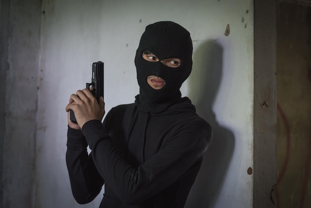 Man robber thief wear mask holding gun hiding armed waiting criminal