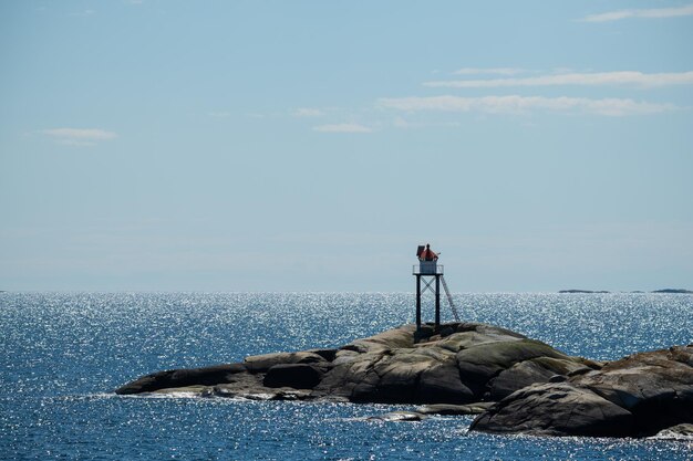 Foto uomo sulla roccia dal mare contro il cielo