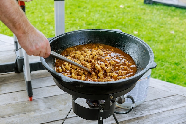 Man roeren kippenvlees in ijzeren ketel