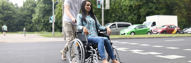 Man rolt een rolstoel met een jonge vrouw