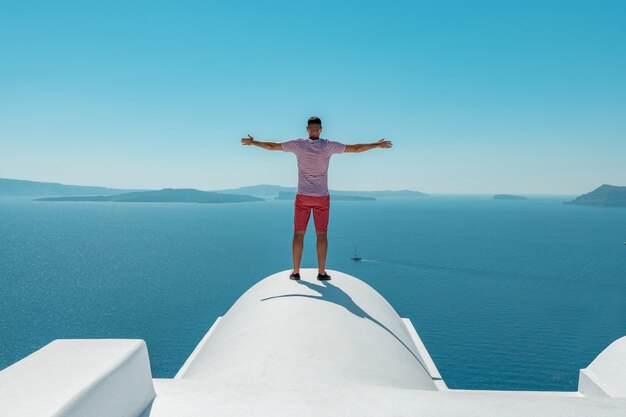 Man on the roof enjoying view of santorini island and caldera in aegean sea greece