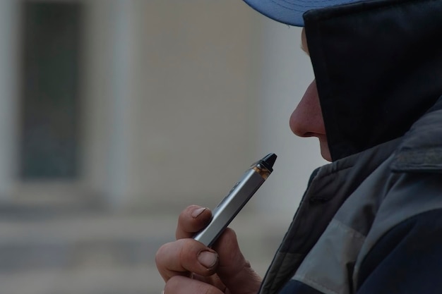 Man rookt nieuwe Vape Pod-systeem inhaleert en ademt damp van elektronische sigaret vaping concept selectieve focus afgezwakt