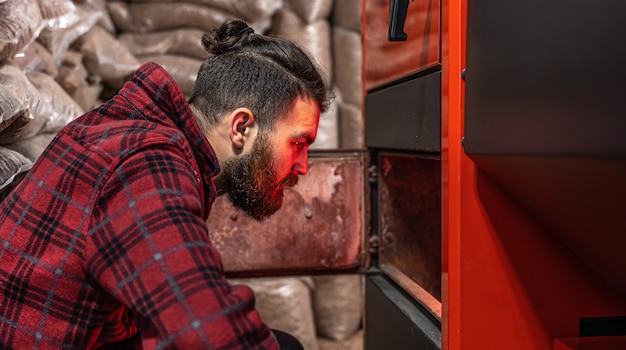 A man in a room with a solid fuel boiler, working on biofuel, economical heating.