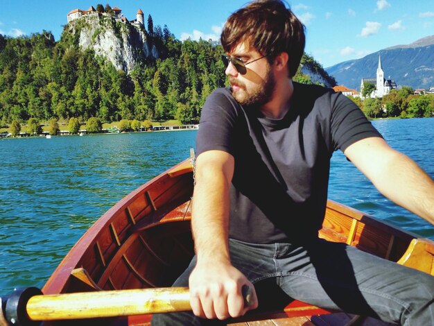 Man rowing boat in lake with mountains in background